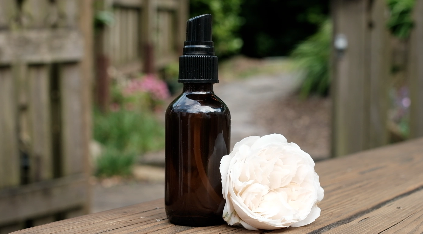 Homemade rose spray in a brown bottle with a white rose beside it